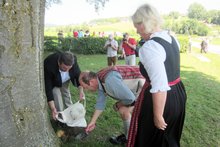 Fotos (von Wilhelm Frickh): Die Pfaffinger Bürgermeisterin Gabriele Aigenstuhler, der Frankenburger Bürgermeister Kons. Johann Baumann und Würfelspiel-Obmann Anton Streicher beim „Erdentausch“ am Haushamerfeld am Freitag, 19. Juni 2015